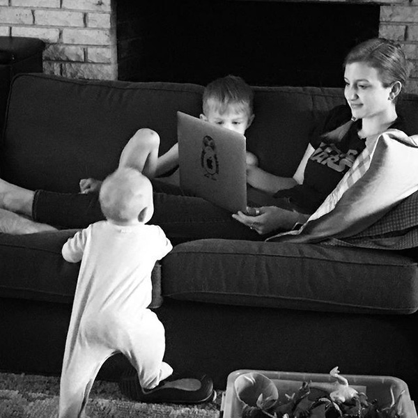 Lifeblue staff Nicole Oakes working on her laptop on the couch with her two kids.